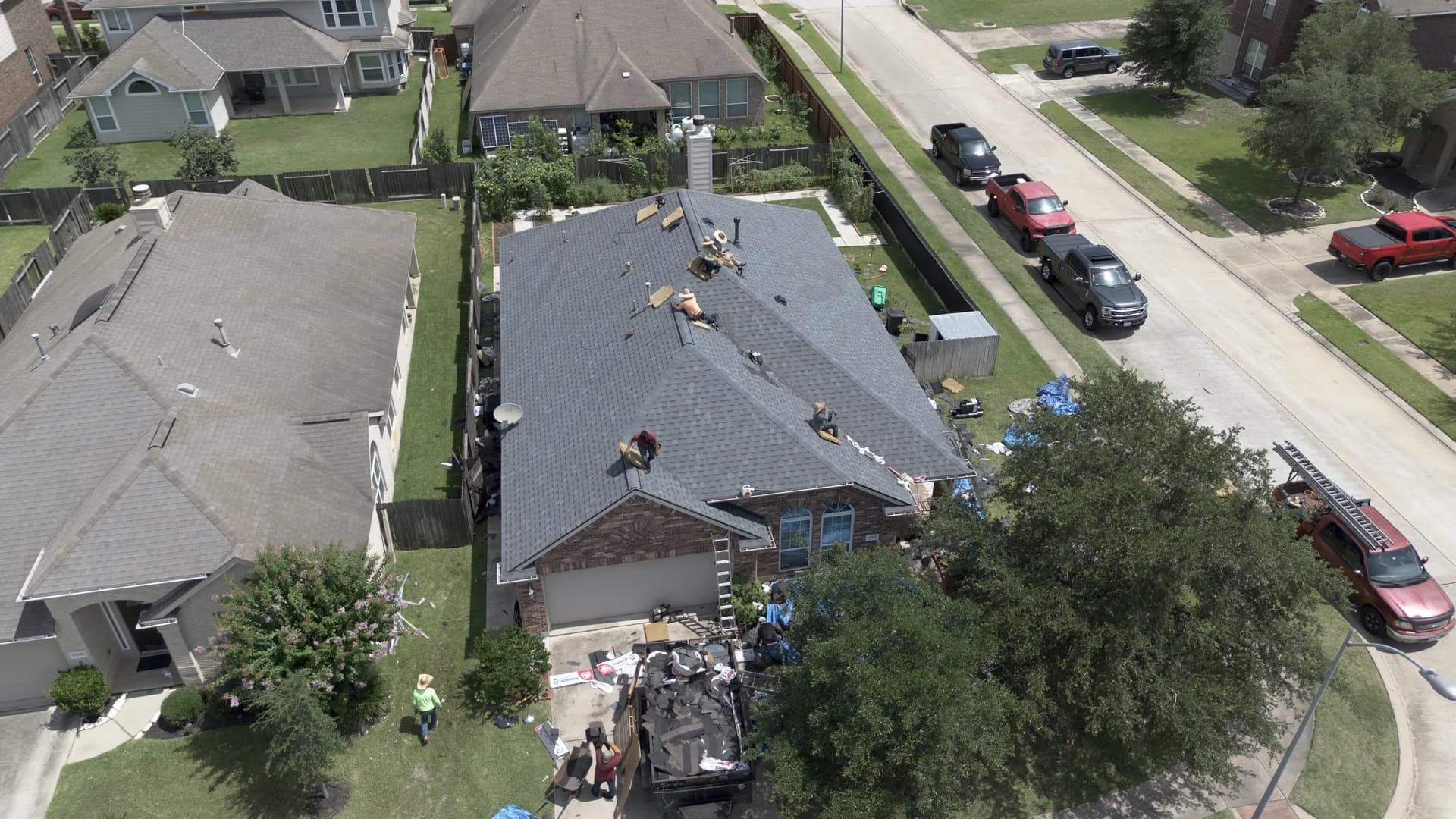 Aerial view of a completed gray architectural shingle roof with a hip roof and dormer
